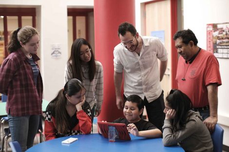 Visiting professor Tom Collins watches a Kids Who Code participate demonstrate his code project