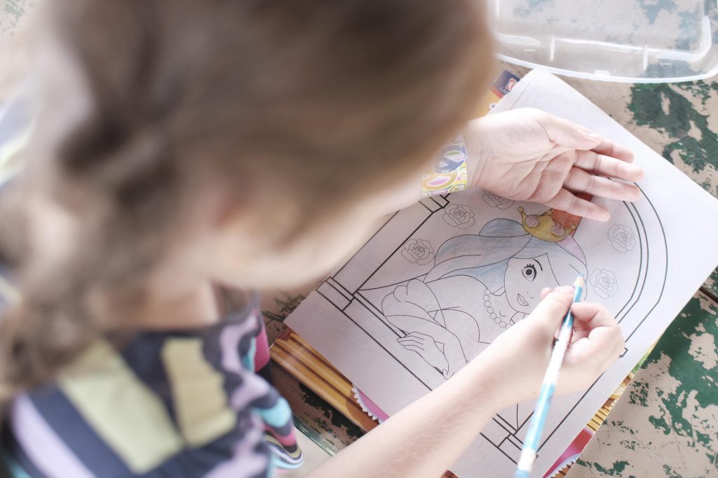 Little girl colors a princess's hair blue.