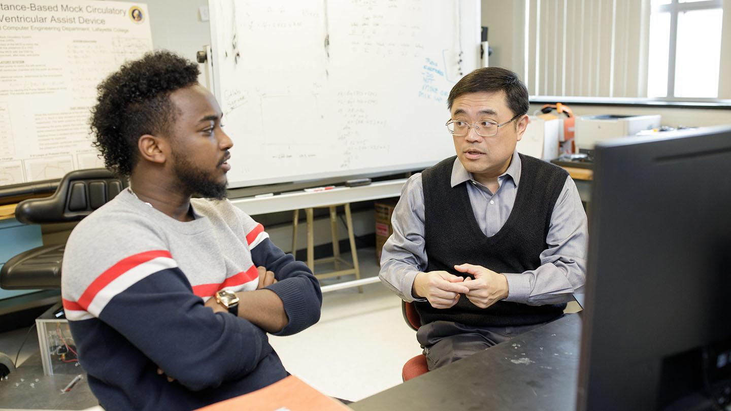 Robson Adem '19 and Yi-Choung Yu talk in a classroom.