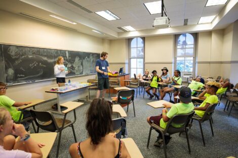 A student explains the activity to a group of teens