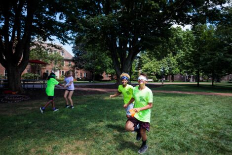 One teen in the community leads another one who is blindfolded in a race