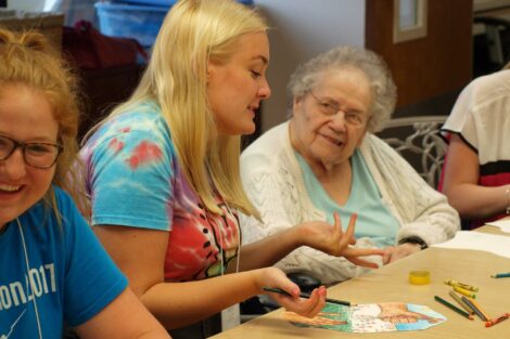 Student speaks with elderly woman as they color together
