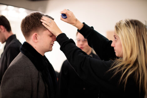 students prepare hair and makeup backstage