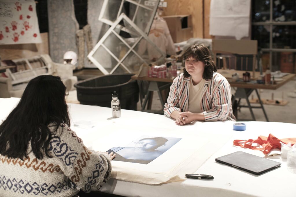 Kim Altomare speaks with a student about the bead work over a drawing