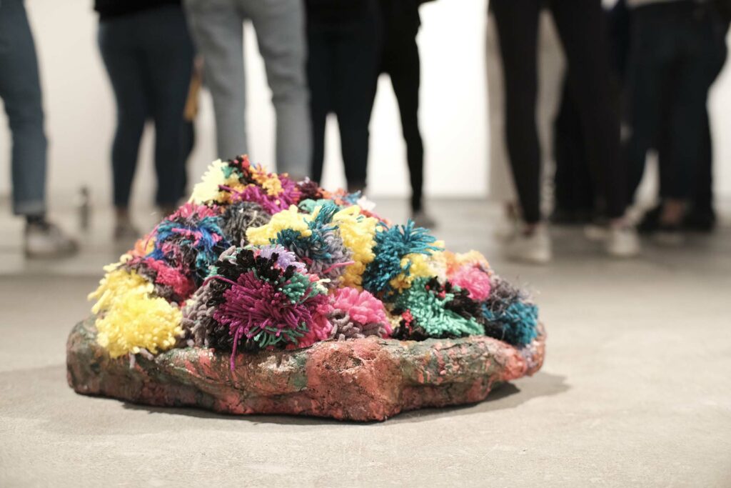 A pile of pom poms fills a sculptural dish