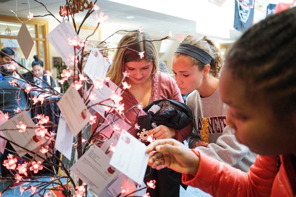 Students stand at a tree and select tags.