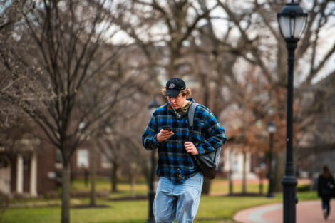 A student looks at his phone while walking on campus on the first day of spring semester.