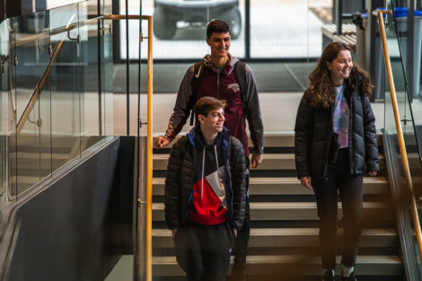 Three students walk down steps in Rockwell Integrated Sciences Center on the first day of spring semester.