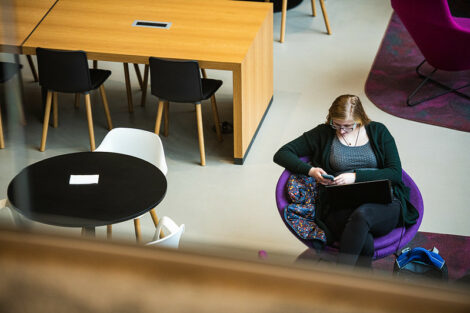 A student uses her smartphone while sitting in Rockwell Integrated Sciences Center on the first day of spring semester.