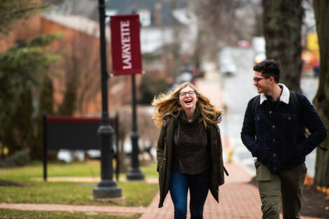 A student laughs while talking with a friend and walking on High Street on campus on the first day of spring semester.