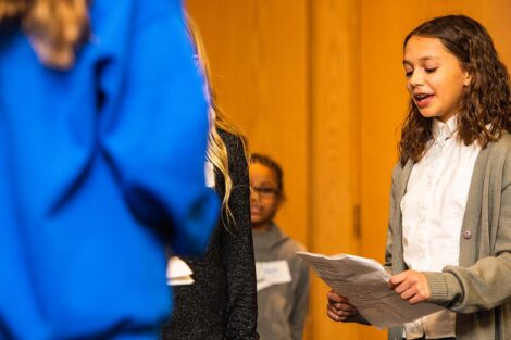 A middle school student reads from a script.