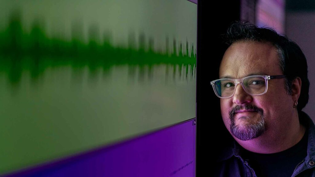 Chris Badami stands next to sound waves
