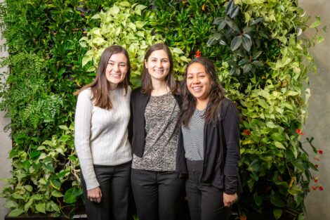 Student externs pose with host in front of a green wall