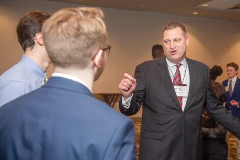 Alum points as he makes a point in a group of students