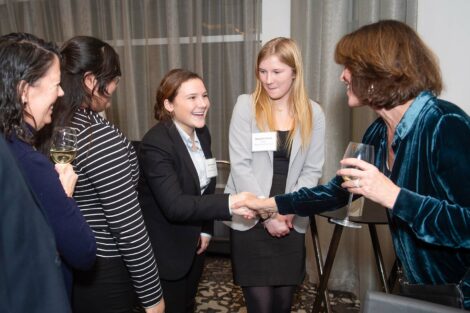 Student shakes hands with an alum as her peers watch