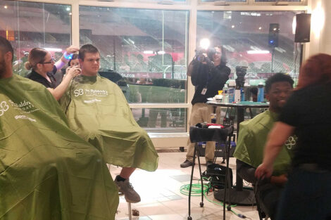 A large group of students gather in Kirby Sports Hall to watch as fellow students get their heads shaved for a cancer charity.