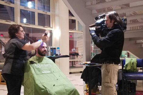 A WFMZ cameraman films a student getting his head shaved for a cancer charity event.