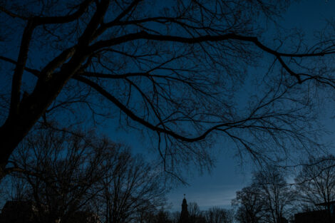 Colton chapel sihlouetted against a blue winter sky surrounded by trees.