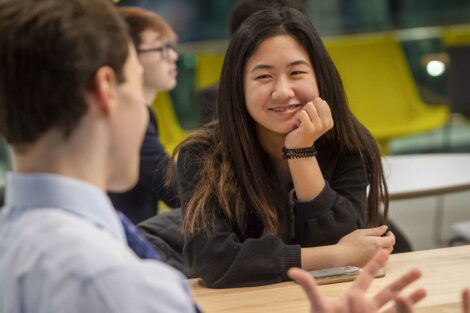 Student smiles as another student speaks