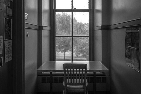 A desk and chair in front of a tall window.