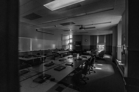 Black and white image of desks and chairs in an empty classroom of Pardee Hall.