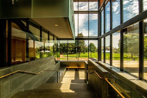 Stairs in Skillman Library. View from the window is a blue sky and the Quad.