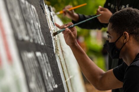 Two youth paint the wall