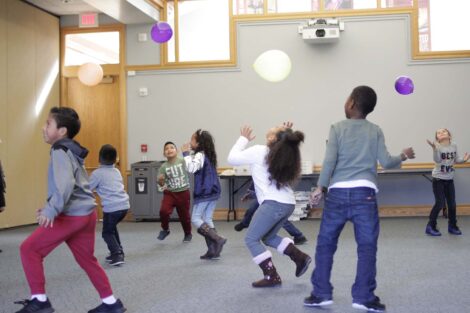 Elementary students chase balloons in activity