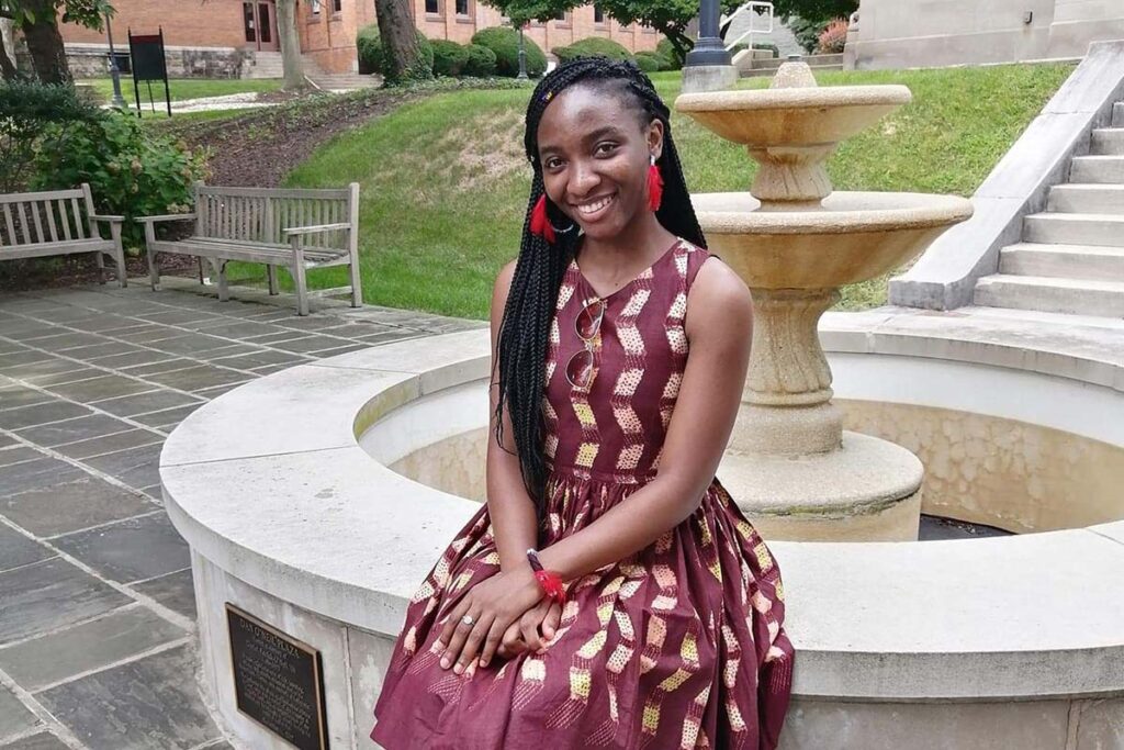 portrait of Jelissa Kamguem ’23, sitting outside on the ledge of a fountain