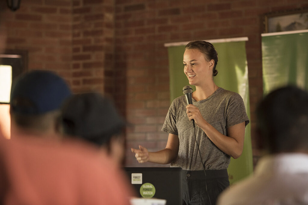 Liz Cole Bourgault ’13 holds a microphone and speaks to a group of people.