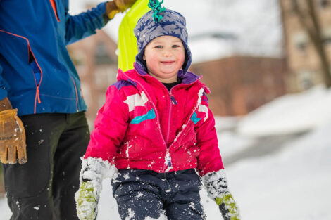 a young child is bundled up in the snow on campus