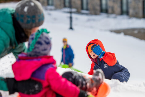 a family sleds down a hill in the snow near OESCLE