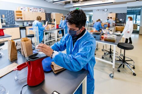 a student in a mask in a biology lab in Rockwell measures popcorn