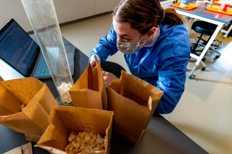 a student in a mask in a biology lab in Rockwell measures popcorn