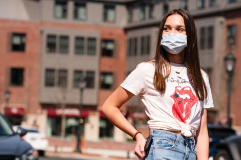 A masked student with their hand on their hip, outside of McCartney