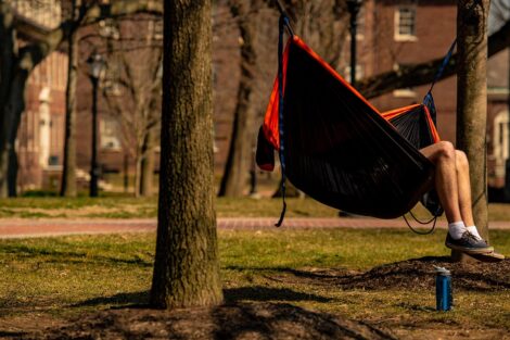 A student's legs hang out of a hammock on the Quad.