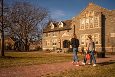 Two students walk on a path in front of Hogg Hall.