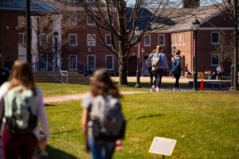 Masked students walk across the grass of the Quad.