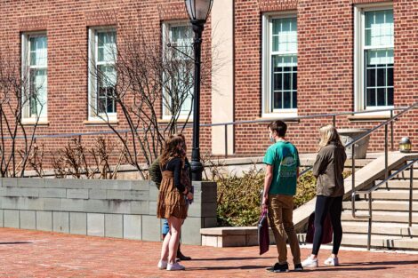 Three masked students talk to each other in a small group outside of Acopian Engineering Building.