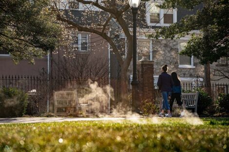 Steam escapes a vent in the Quad; students walk.