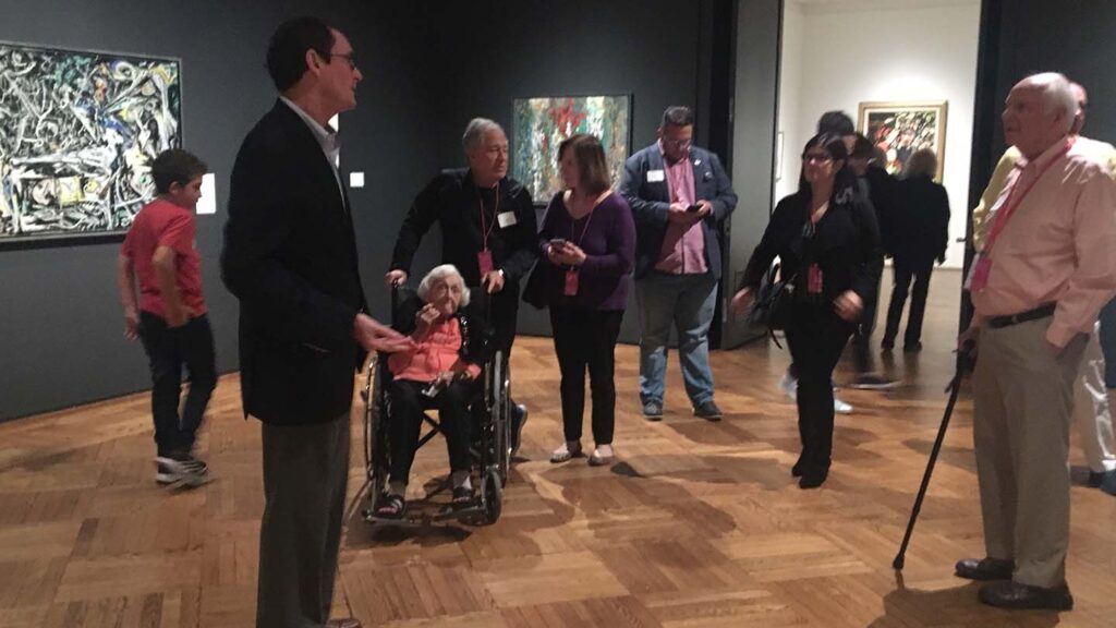 People stand around Bob Mattison in a gallery and ask him questions
