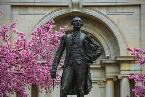 A statue of the Marquis de Lafayette, in front of Colton Chapel and pink trees.