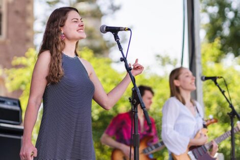 students sing and play guitar in band on a stage on the Quad