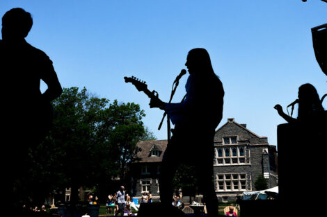 shadowed students play in a band on a stage on the Quad