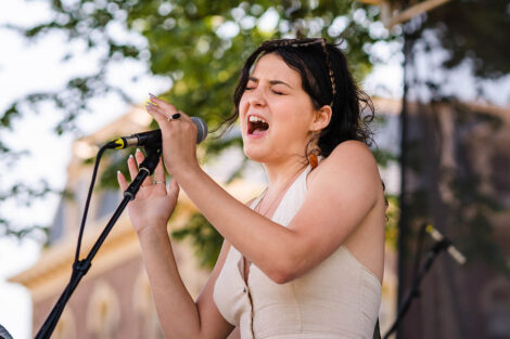 student sings into a mic on a stage on the Quad