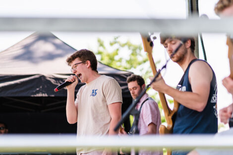 students sing and play guitar in band on a stage on the Quad