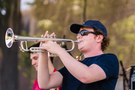student plays trumpet on stage on Quad