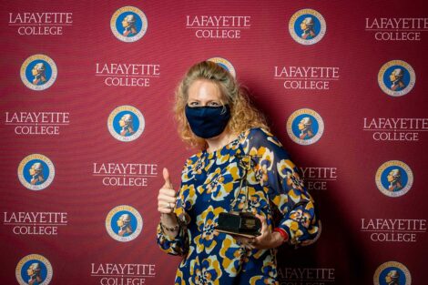Janine Block '94 holding Aaron O. Hoff Award and standing in front of Lafayette College backdrop