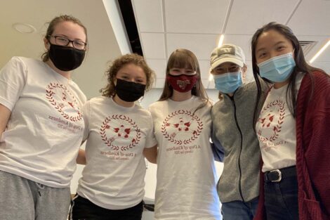 Five masked students stand next to each other all wearing Literacy Day shirts