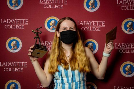 Nicole Segalini '21 holding Aaron O. Hoff Award statue and standing in front of Lafayette College backdrop